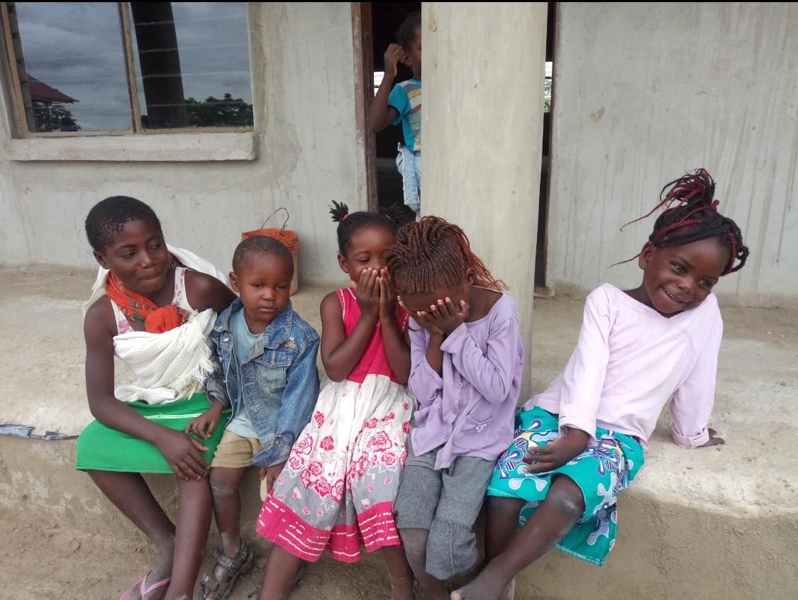 Children sitting in front of school.